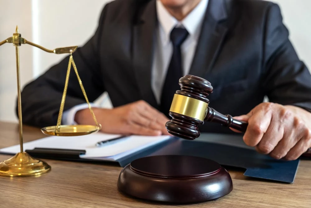 Legal law, advice and justice concept, counselor lawyer or notary working on a documents and report of the important case and wooden gavel, brass scale on table in courtroom.