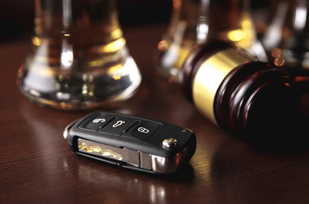 Drinking and driving concept. Car key on a wooden table, pub