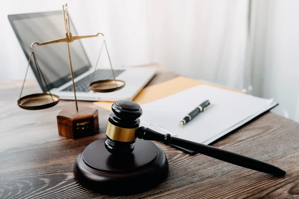 Business and lawyers discussing contract papers with brass scale on desk in office