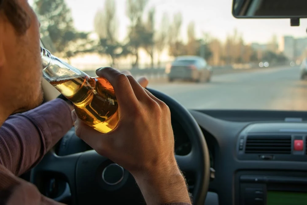 A man drinking alcohol while driving
