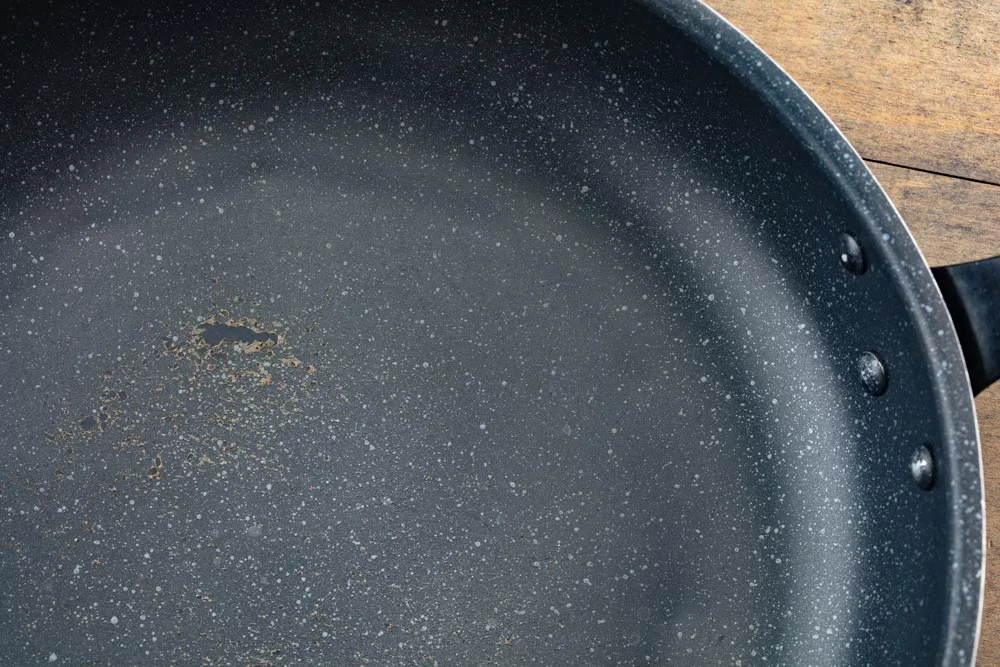 Nonstick coating of a frying pan going bad. Peeling or disintegrating nonstick PTFE coating of a pan, cookware.
