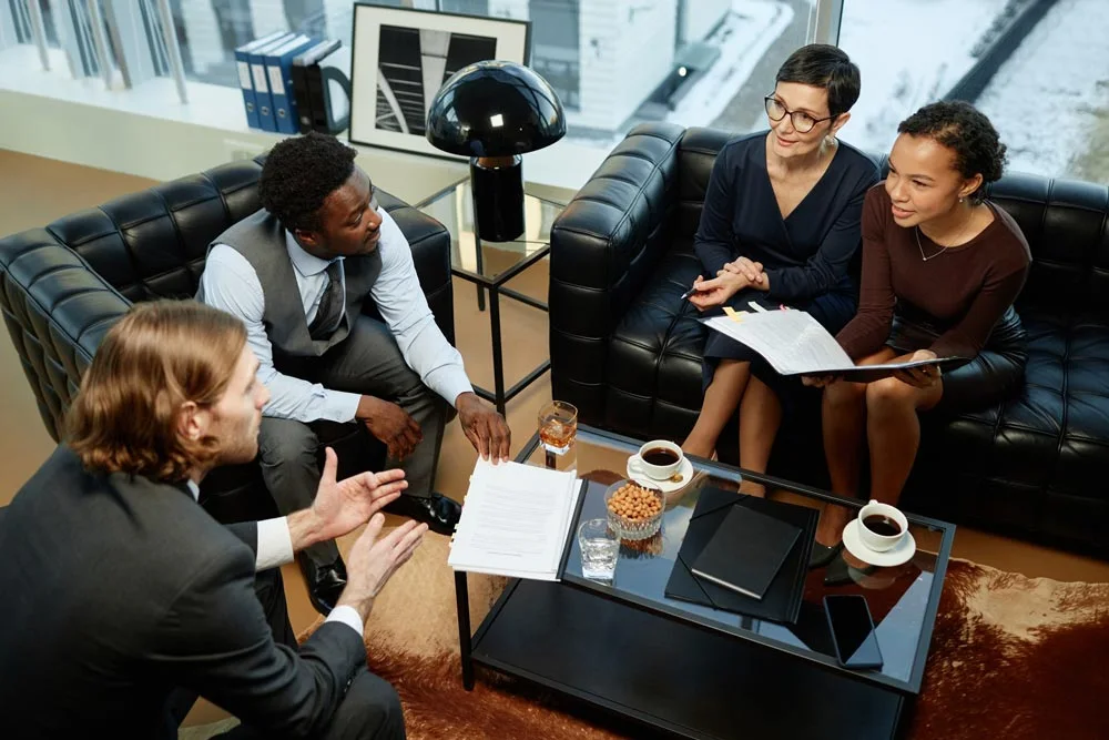 High angle portrait of group of successful business people meeting over coffee table in luxury office